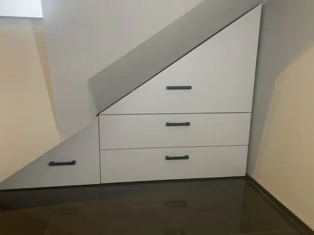 Biała zabudowa pod schodami z szufladami