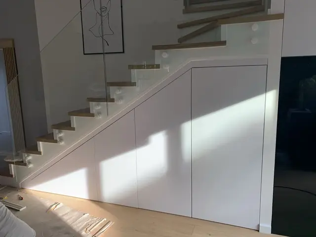 Minimalistyczna biała zabudowa pod schodami